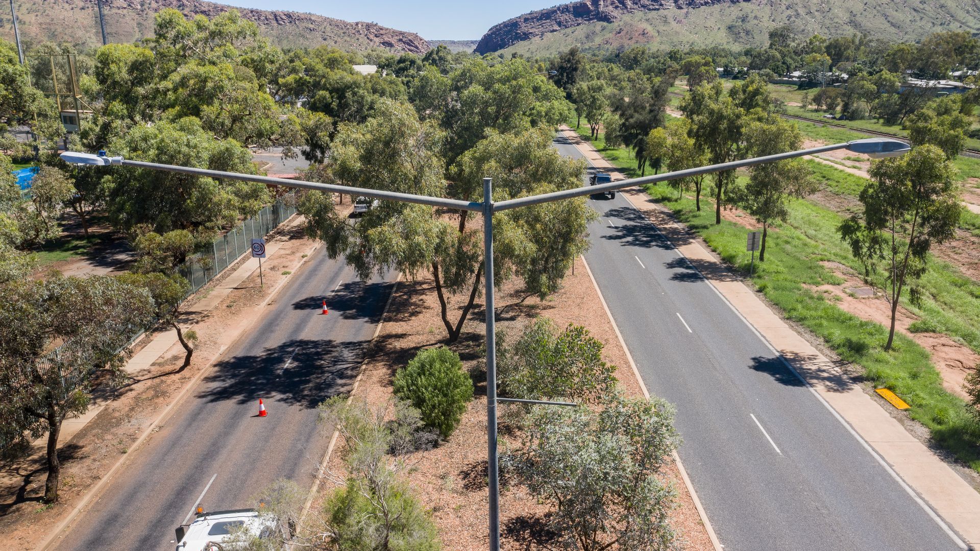 Aerial view of a divided road lined with trees in a dry, hilly landscape