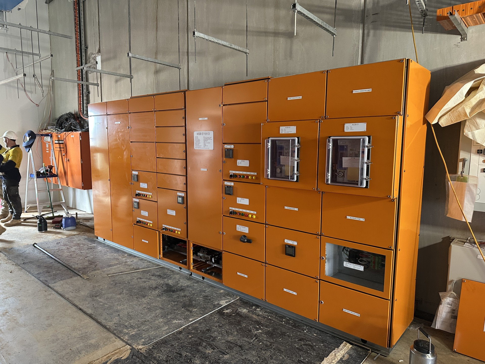 Orange industrial equipment cabinets in a warehouse workshop, with warning labels and control windows