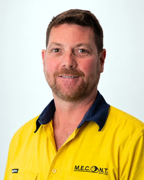 Portrait of a smiling man in a yellow work shirt with navy collar against a light background