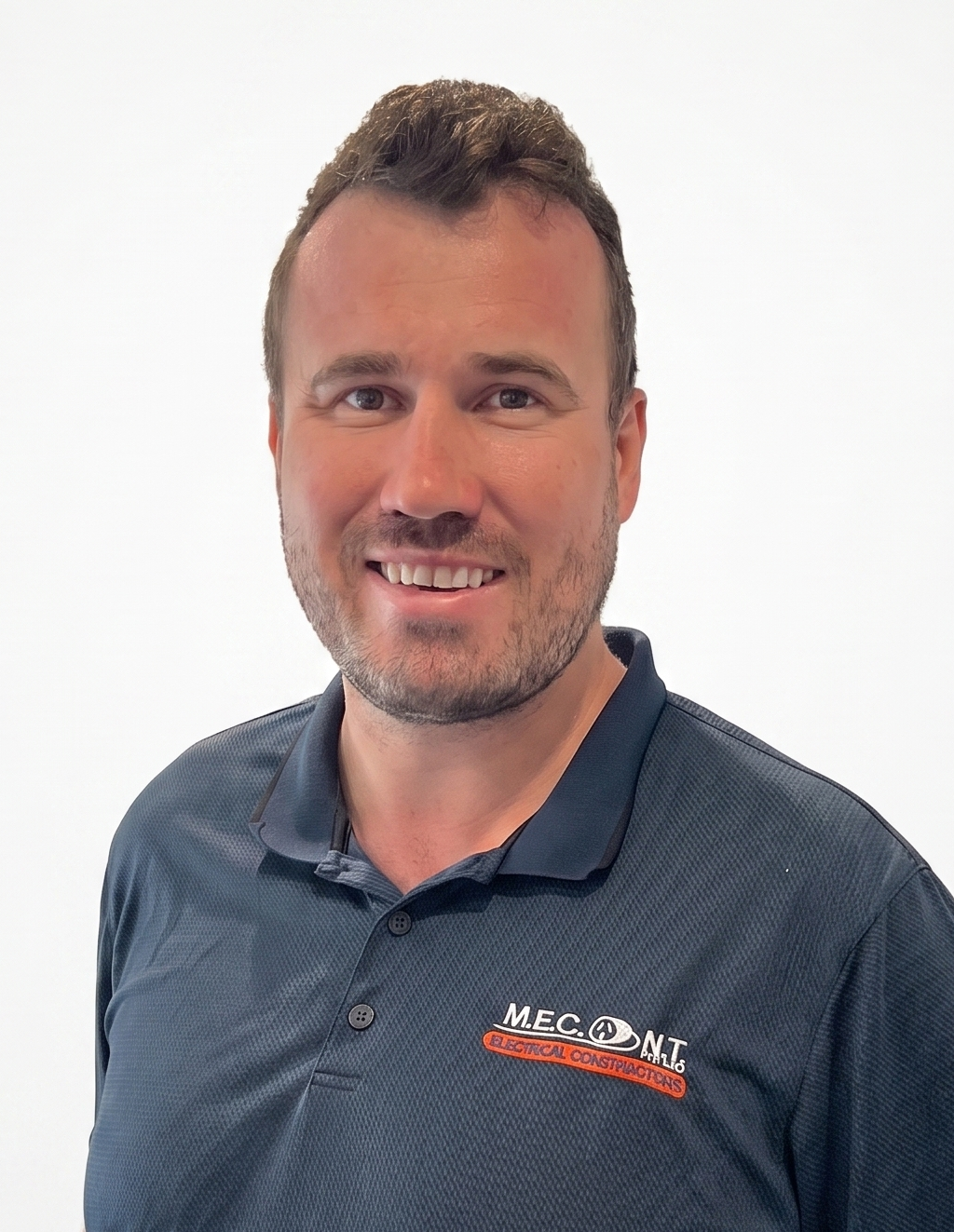 Portrait of a smiling man in a dark blue polo shirt against a white background