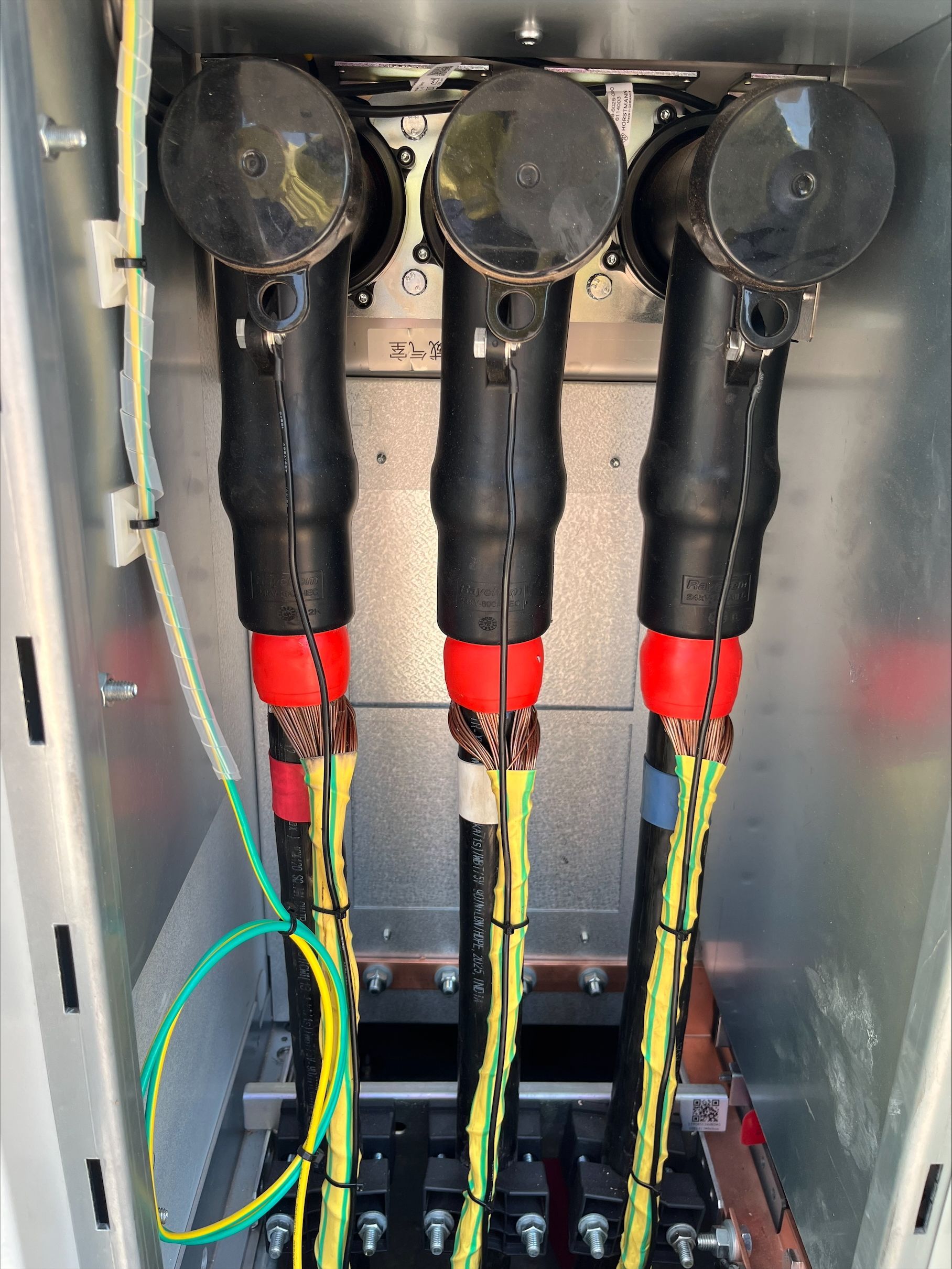 Electrical panel with three black cable connectors and red/yellow wires inside a metal enclosure