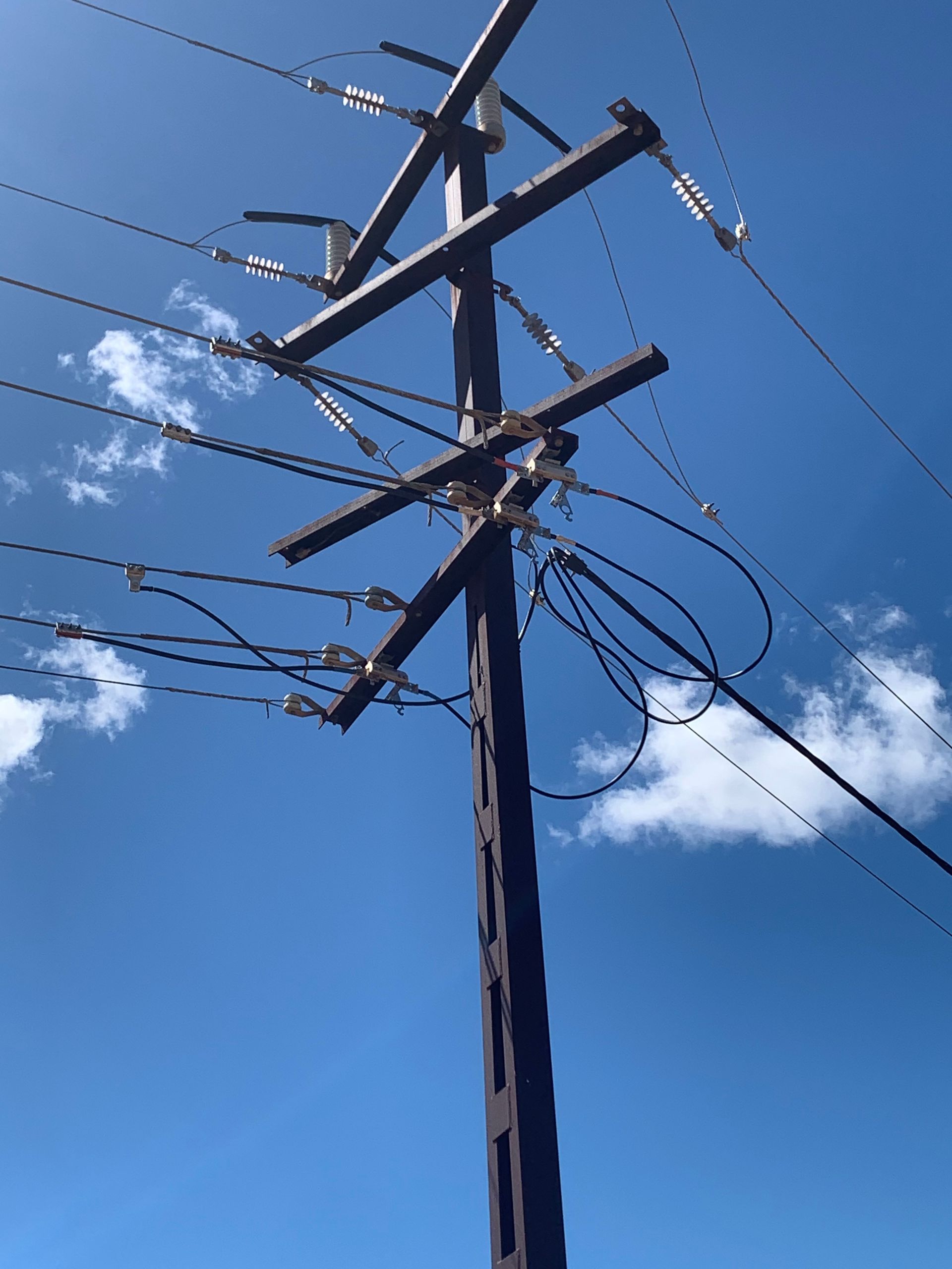 Utility pole with power lines against a blue sky with clouds