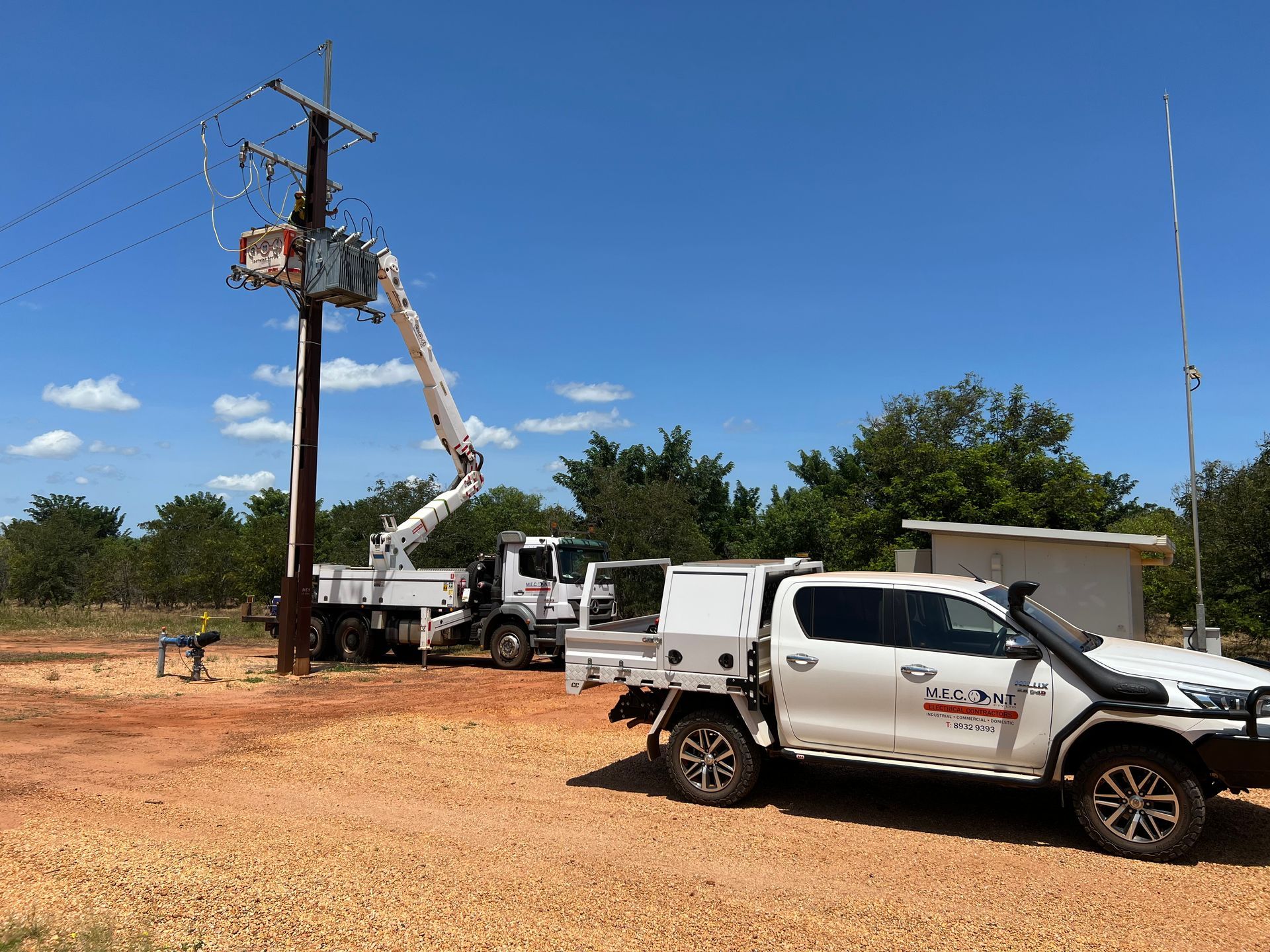 Utility trucks working on a power pole in a dry rural area