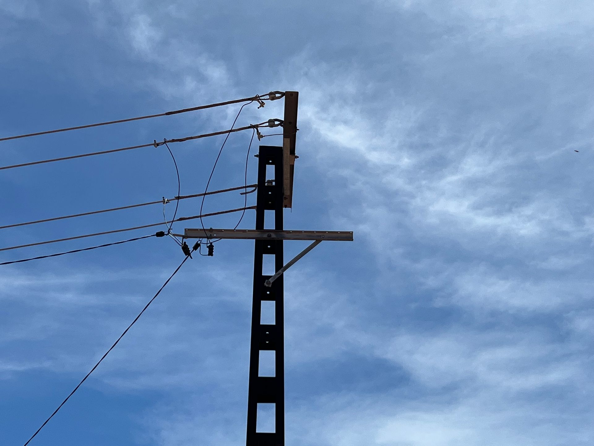 Power lines on a utility pole against a cloudy blue sky