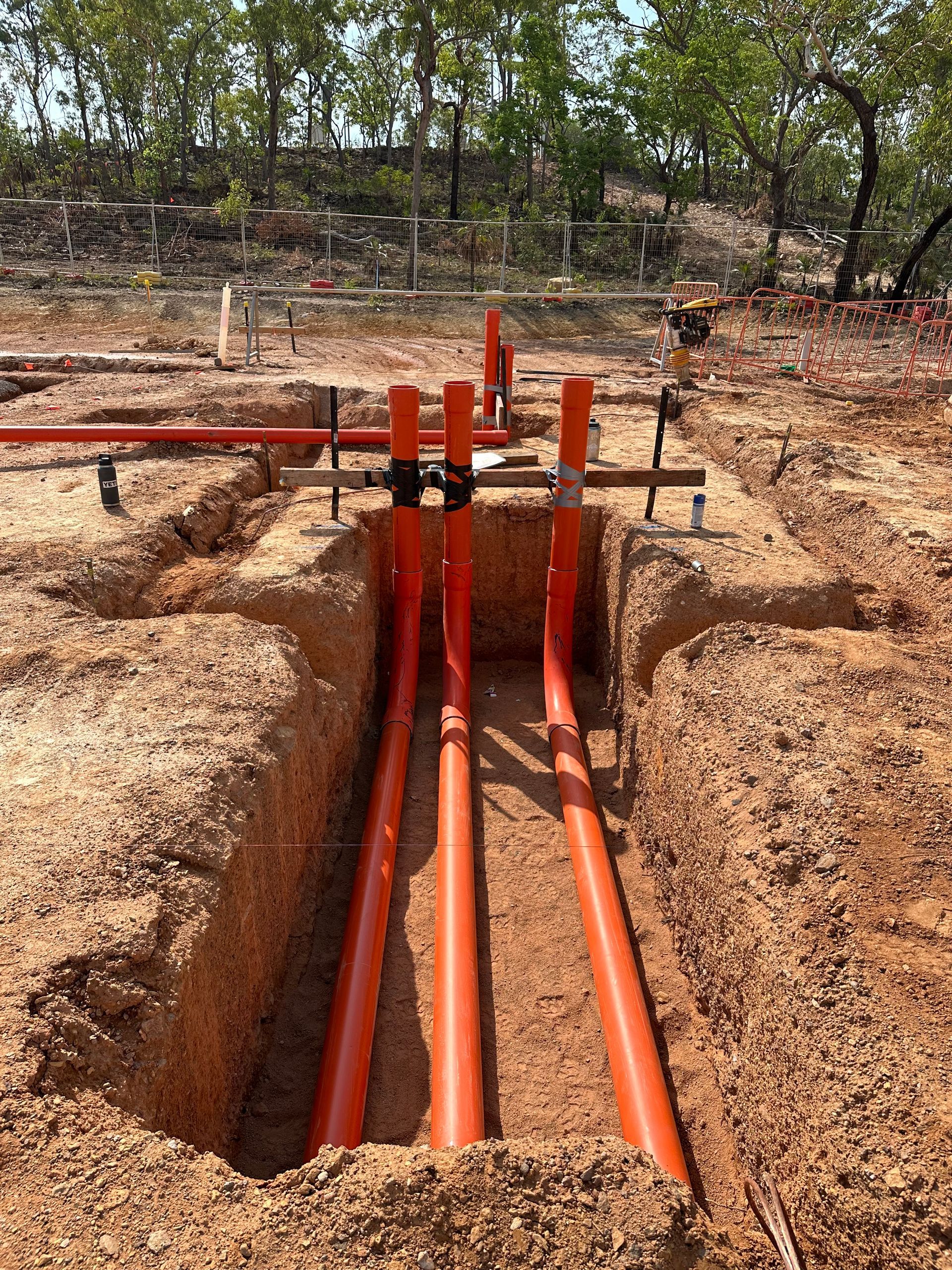 Orange utility pipes installed in a trench at a construction site