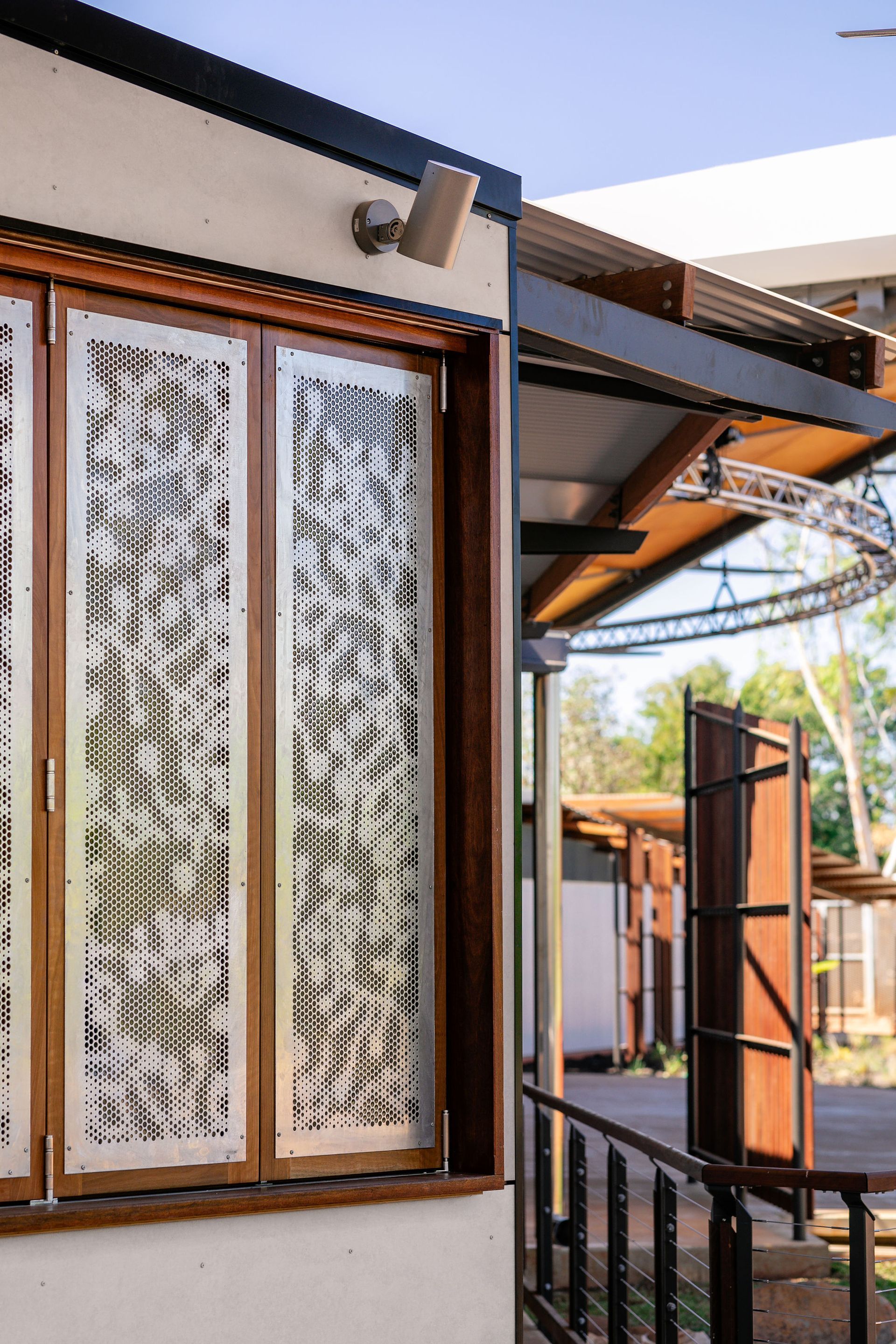 Modern house exterior with wooden-framed windows, metal awning, and a small porch railing