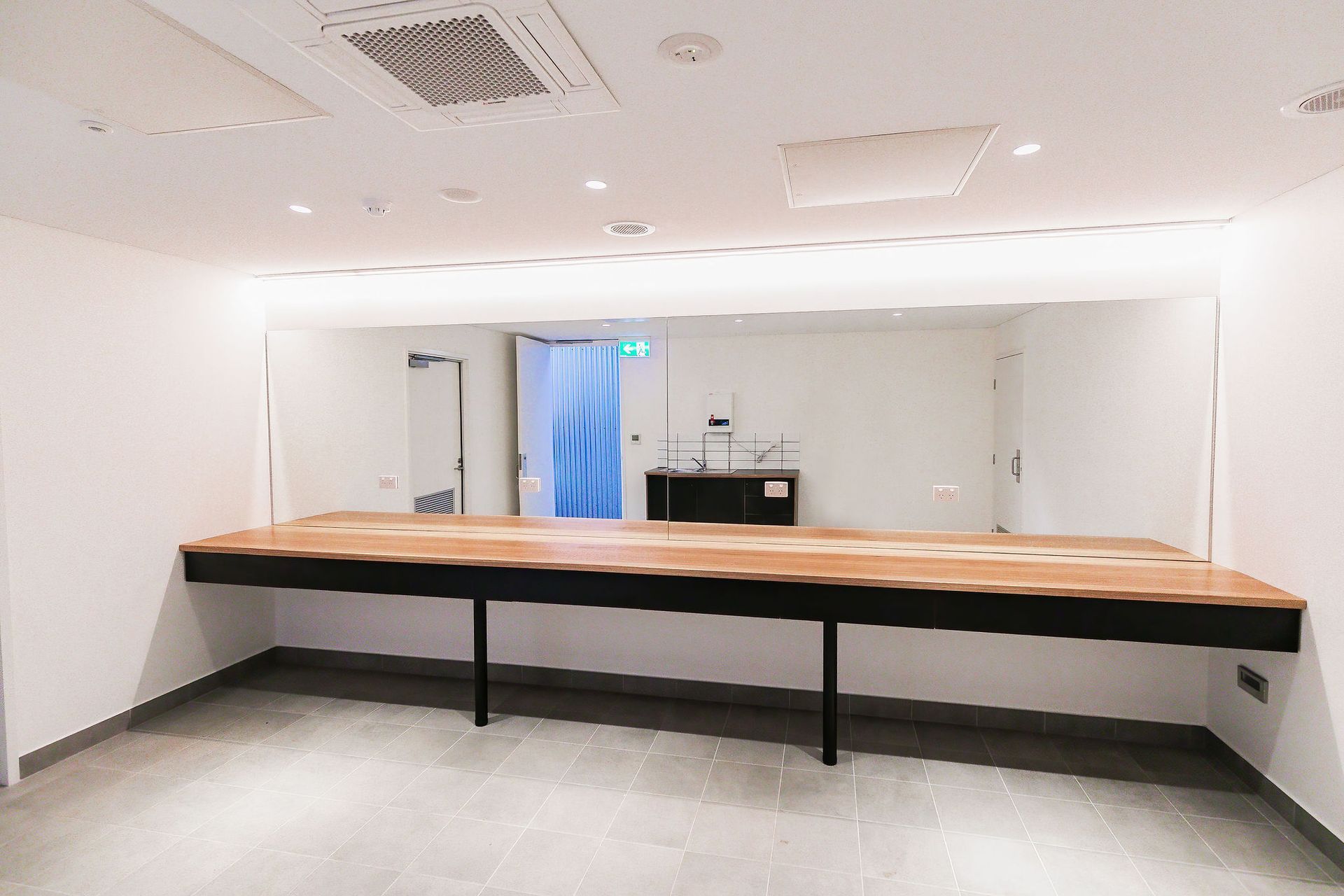 Empty modern room with a long wooden counter, white walls, and bright ceiling lights
