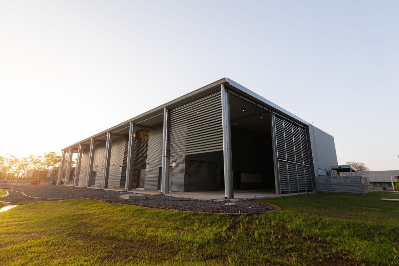 Modern barn-like metal building on a grassy field at sunset