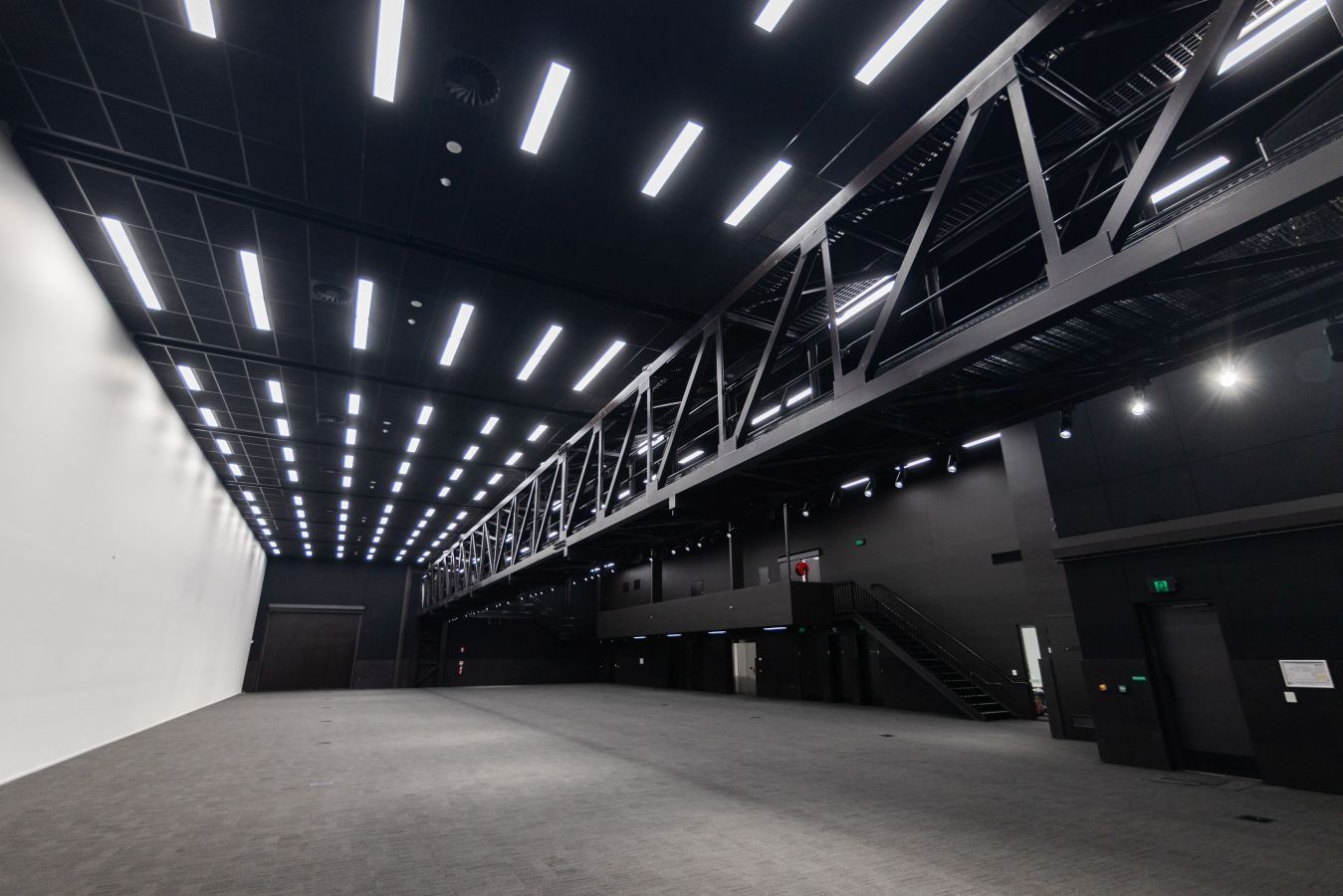 Empty industrial warehouse interior with high ceiling lights and metal truss walkway