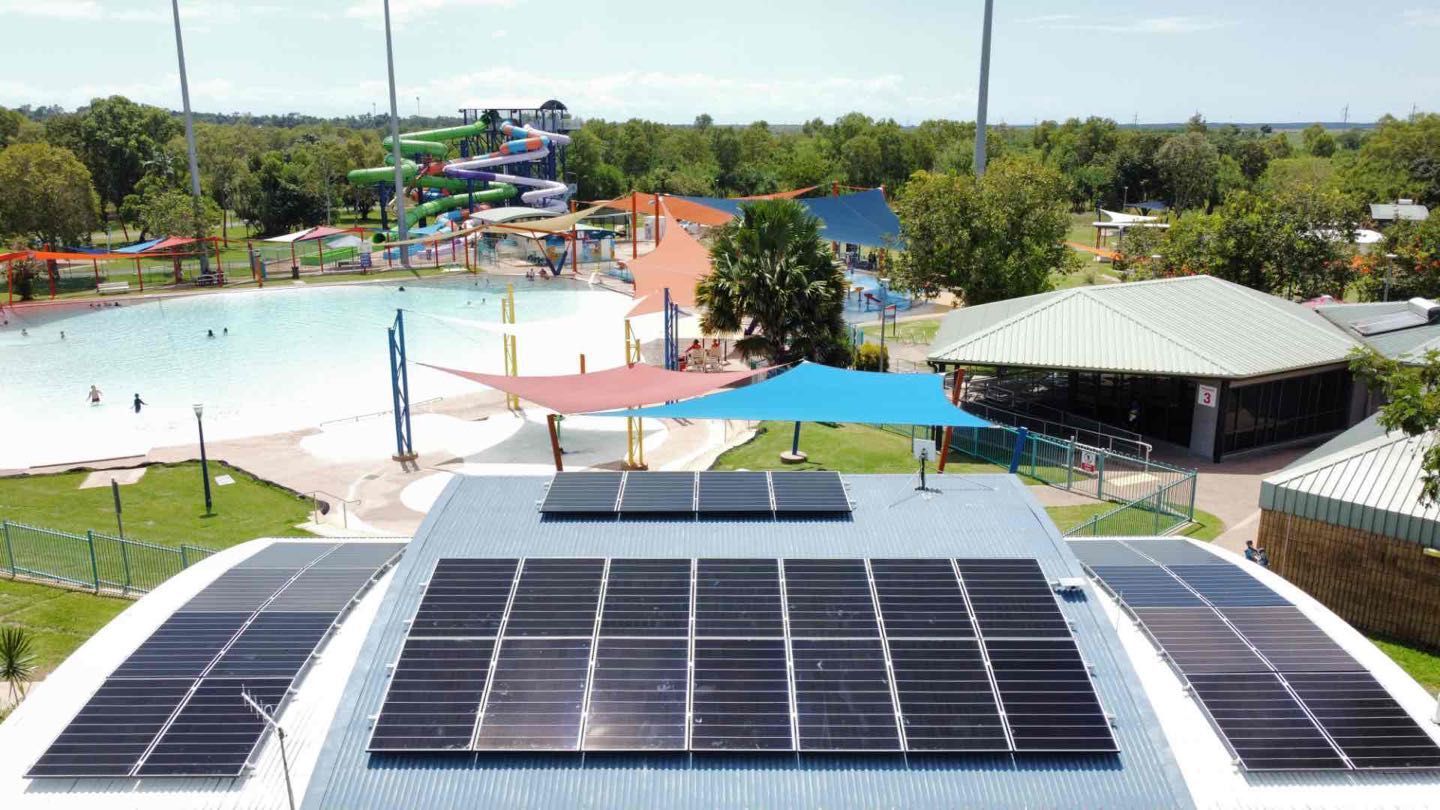 Rooftop solar panels overlooking a water park with slides and a pool on a sunny day