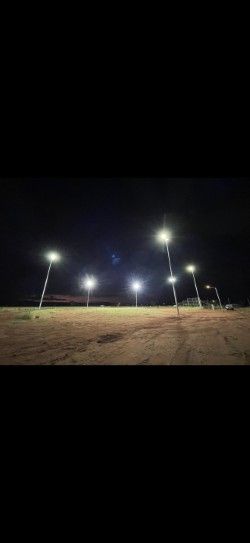 Nighttime soccer field with bright floodlights illuminating an empty grassy pitch