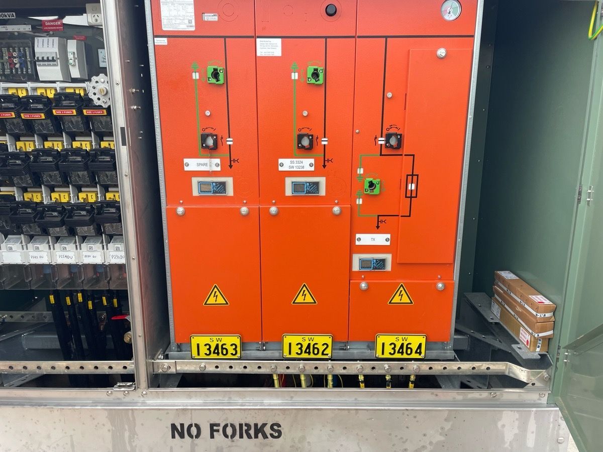 Orange electrical switchgear cabinets in an industrial room, labeled and behind a “NO FORKS” sign