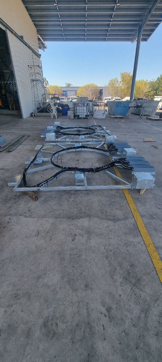 Metal carts with large circular frames lined up on a warehouse loading dock under a canopy.