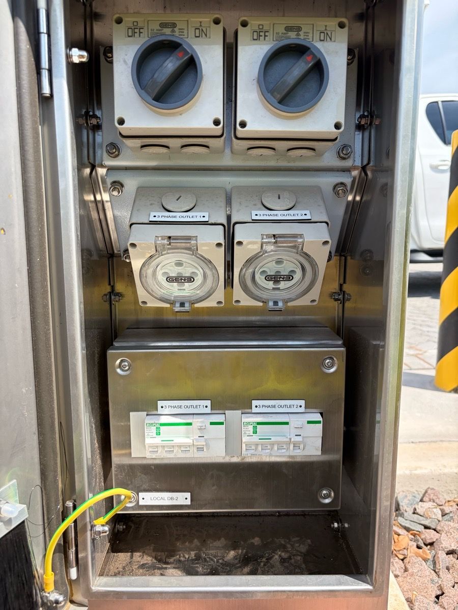 Electrical meter panel with gauges and two circuit breakers inside a metal cabinet.