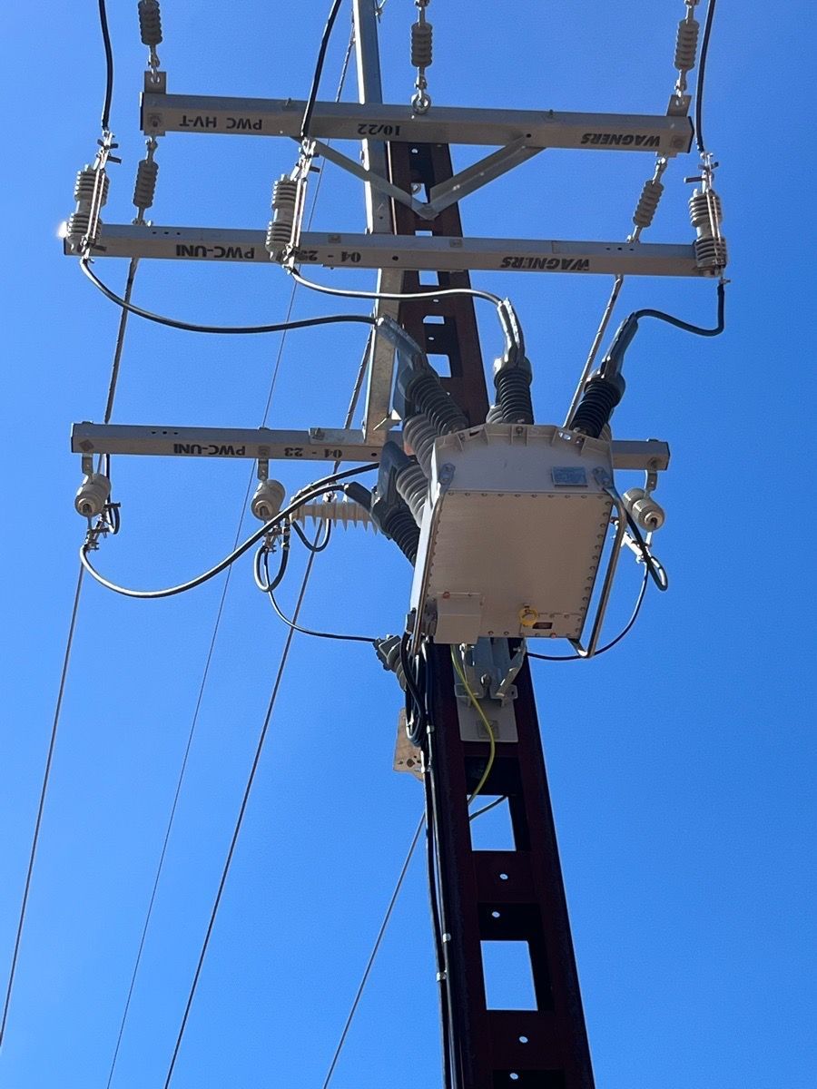 Utility pole with transformers and power lines against a clear blue sky