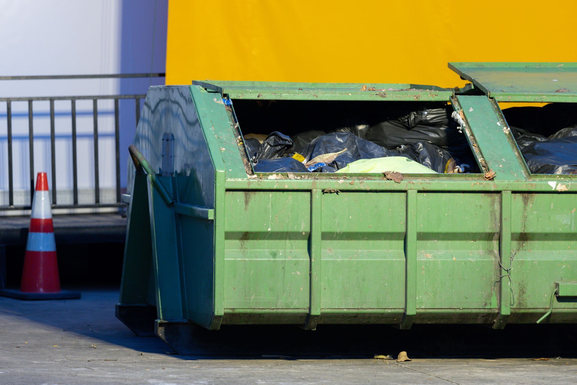 Commercial garbage collection dumpster filled with waste outside a building.