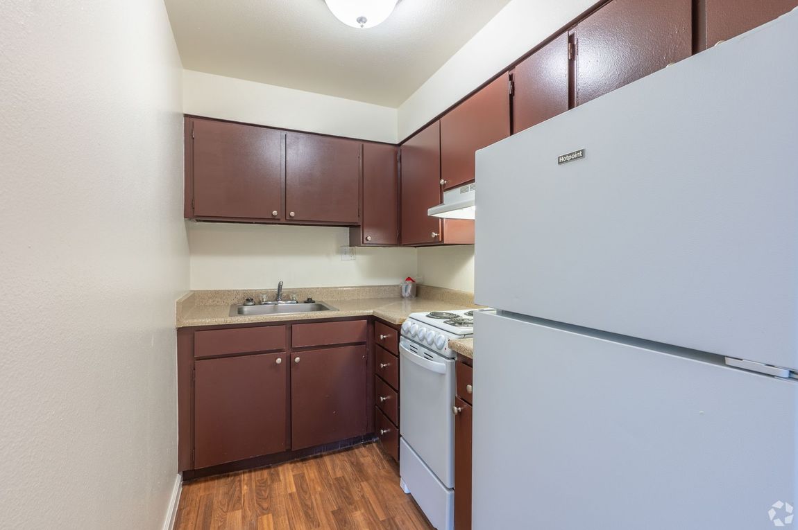 Small kitchen with brown cabinets, white appliances, and wood floor
