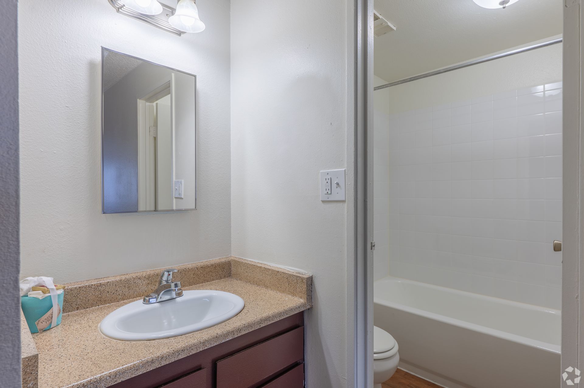 Bathroom vanity with white sink, granite countertop, mirror, and shower stall partition
