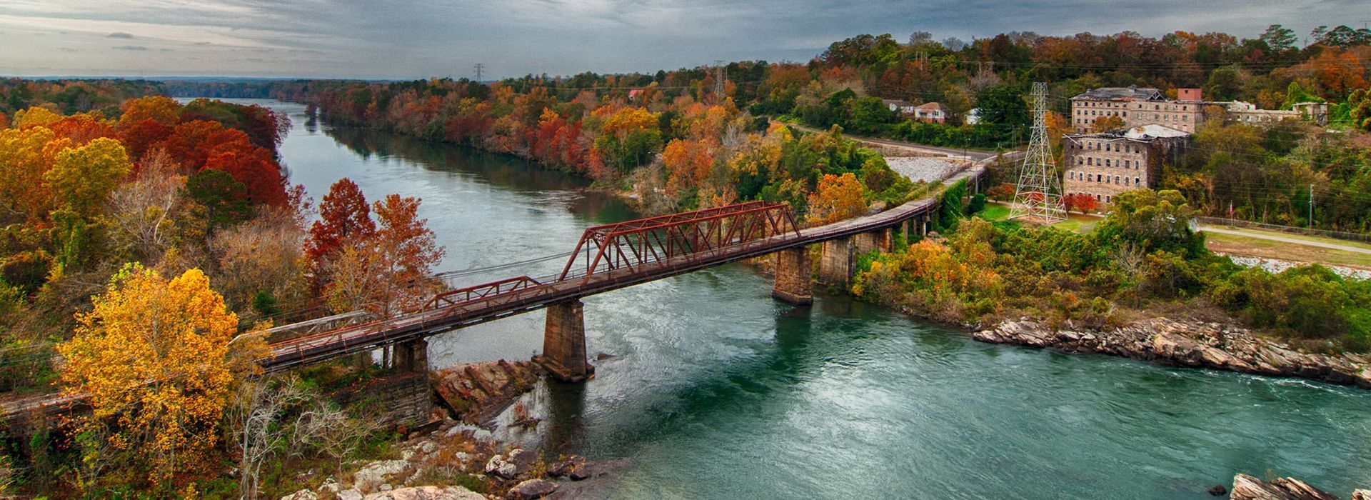 An aerial view of a bridge over a river surrounded by trees.