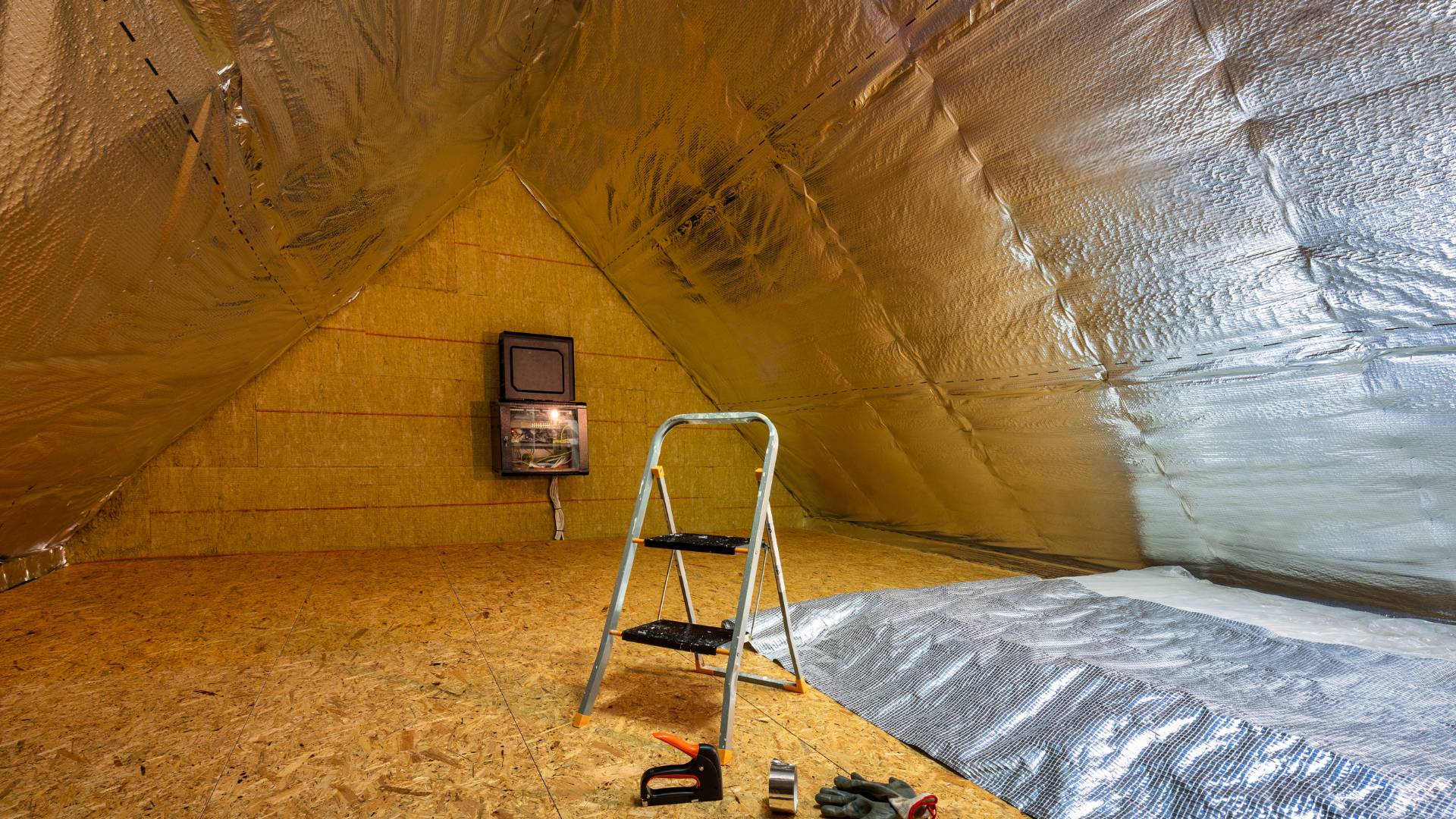 There is a ladder in the attic with insulation on the ceiling.