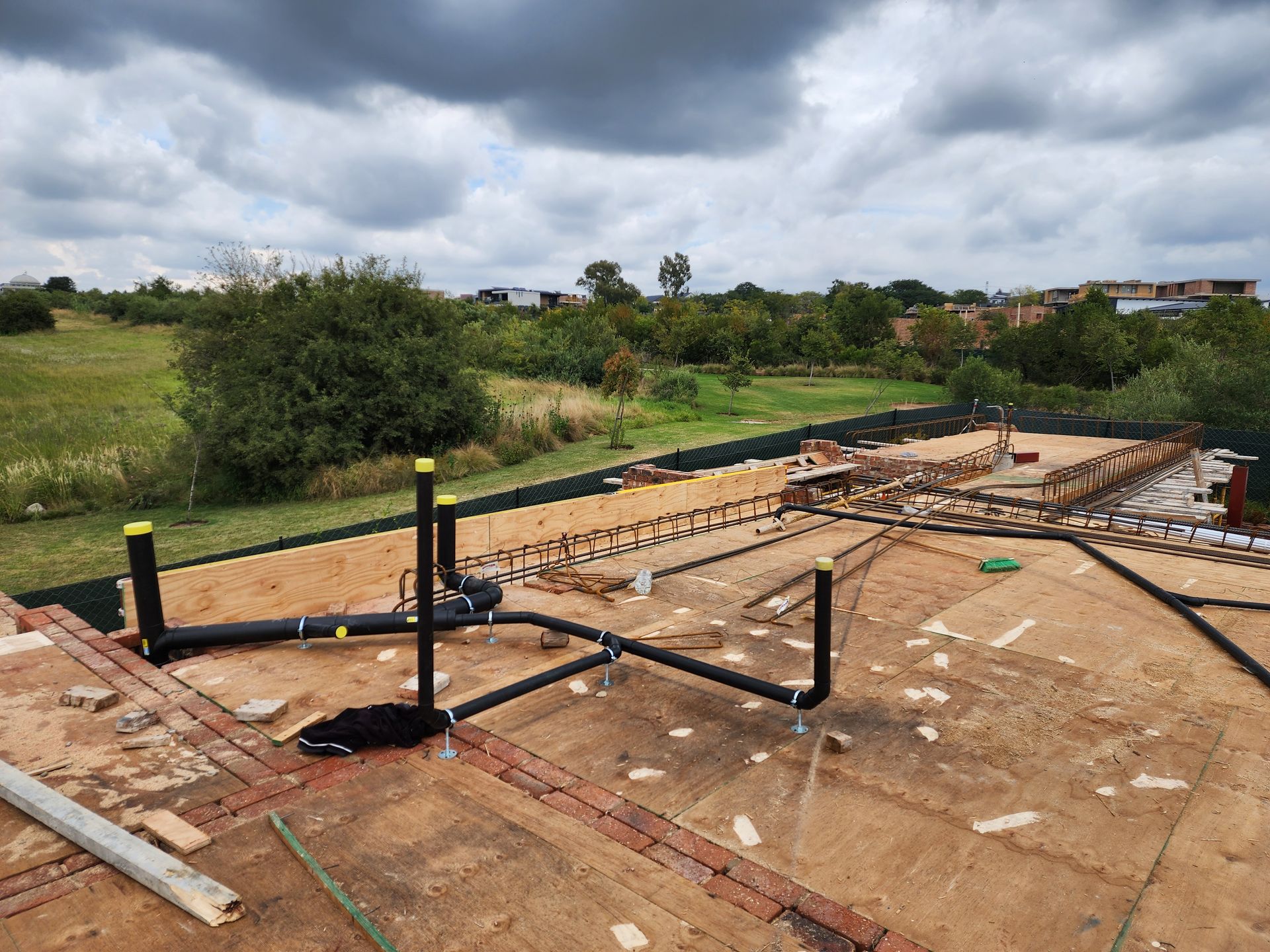 Construction site with wooden foundation framing on a muddy lot under a cloudy sky