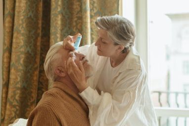 Image of spouse instilling eyedrops for her husband
