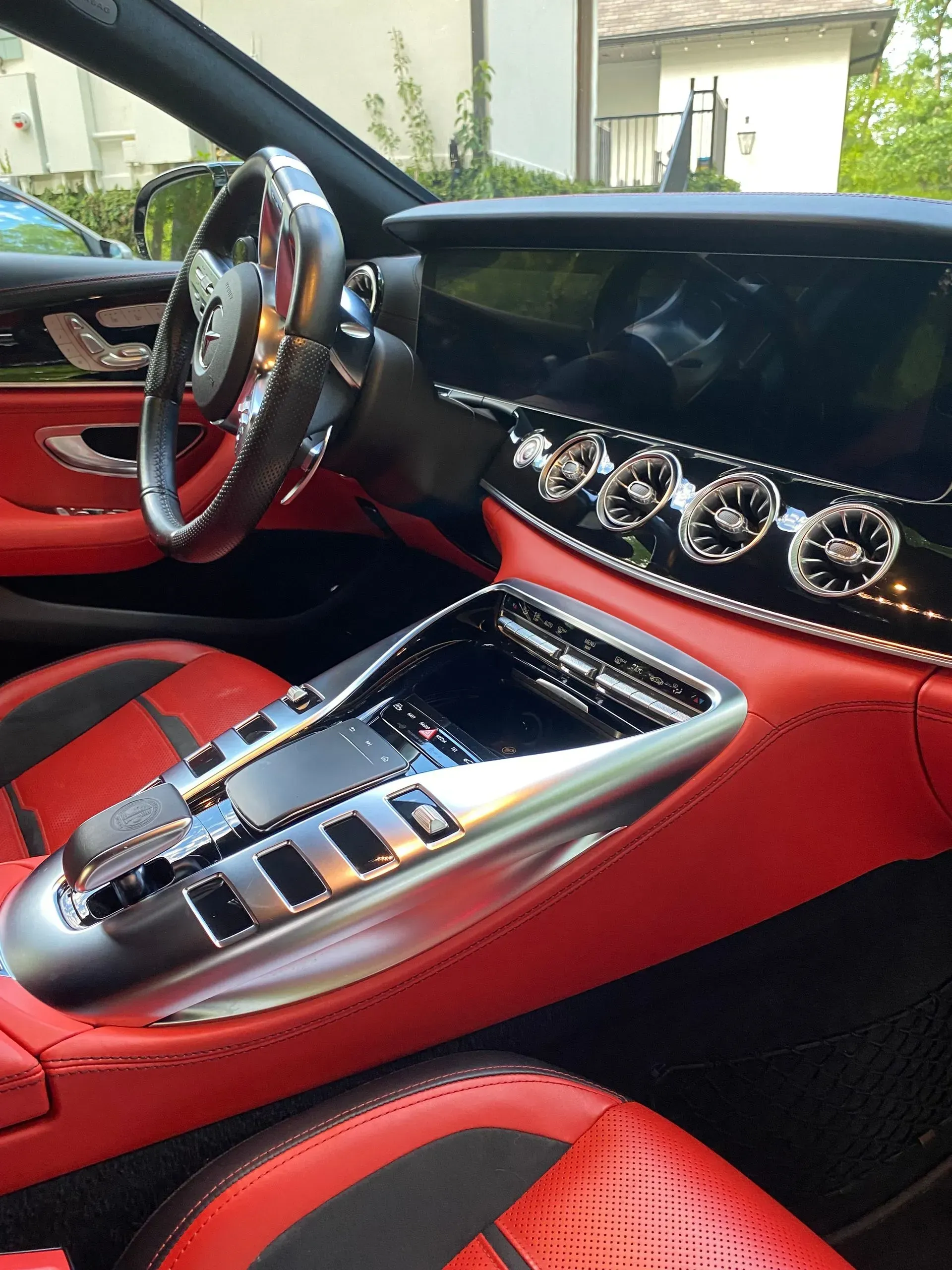 Interior view of a luxury car with a black dashboard and vibrant red leather seats, center console, and steering wheel.