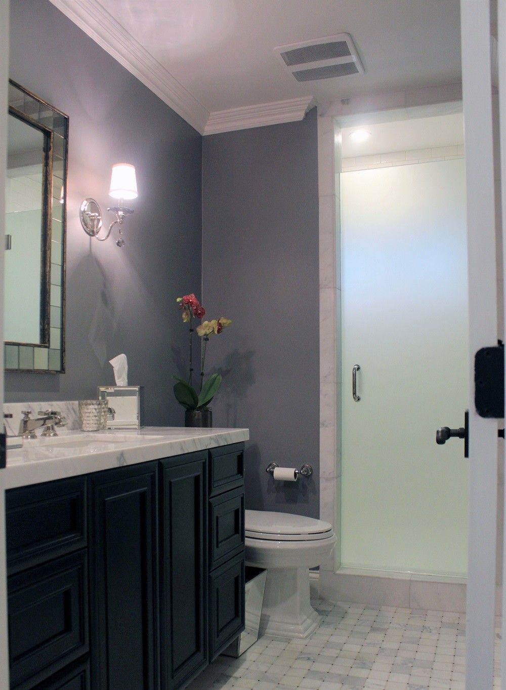 Bathroom with gray walls, black vanity, and frosted glass shower.