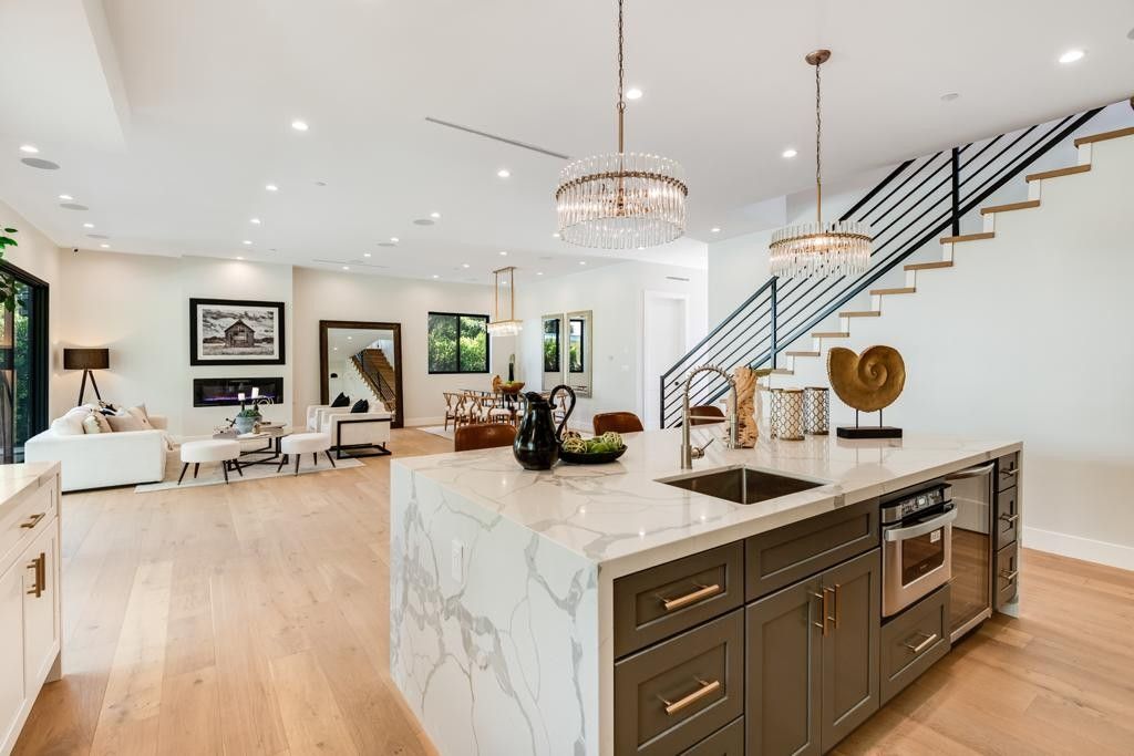 Spacious open-concept kitchen with large island, marble countertop, and staircase in a modern home.