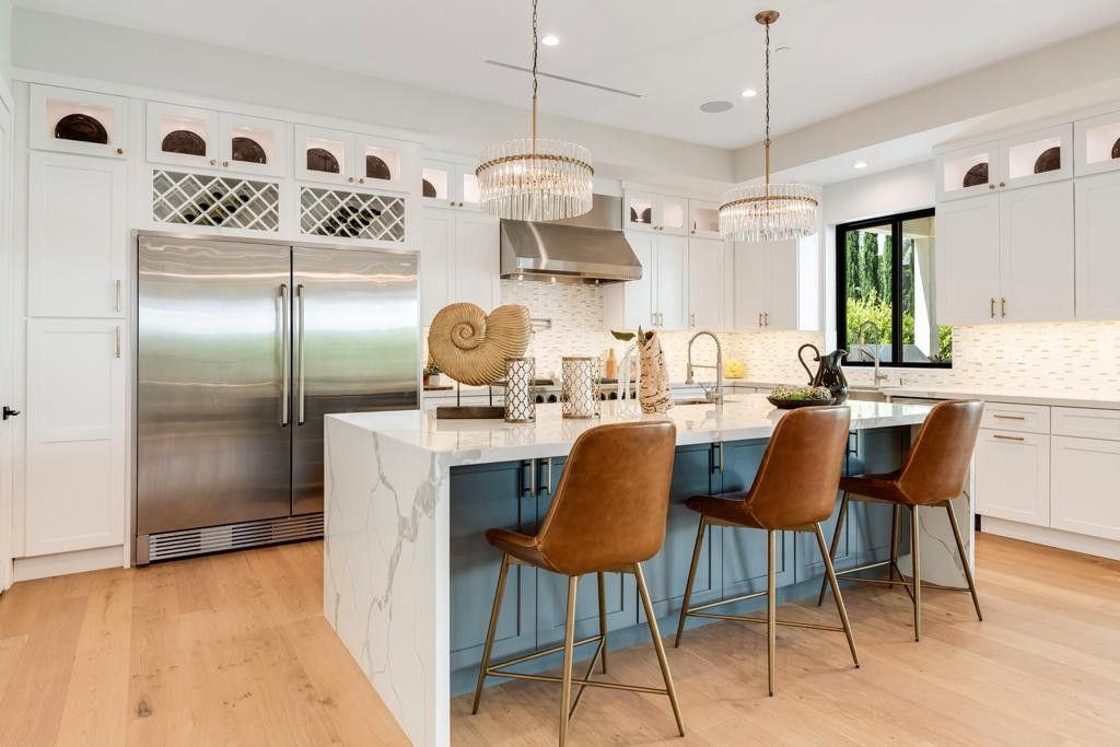 Modern kitchen with blue island, marble countertop, and gold bar stools.