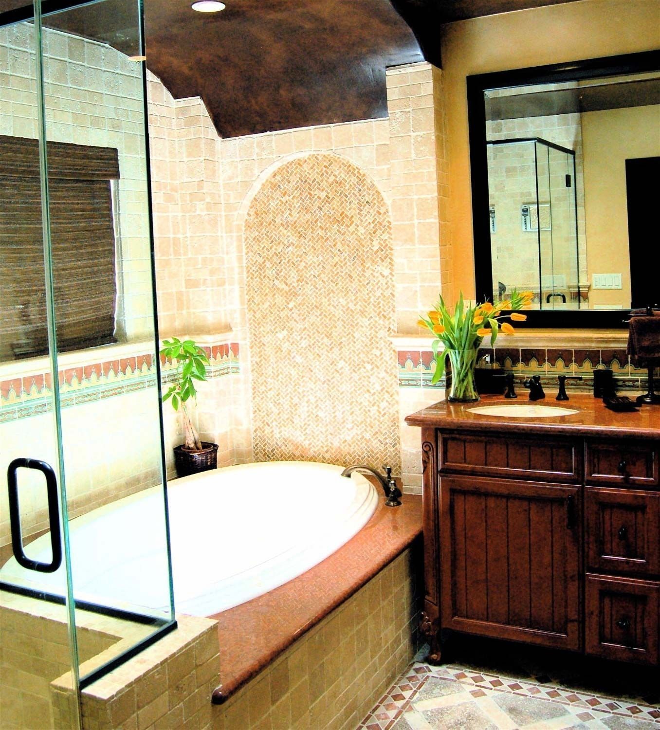 Bathroom with oval tub, arched alcove, and dark wood vanity. Beige tile walls and floor.