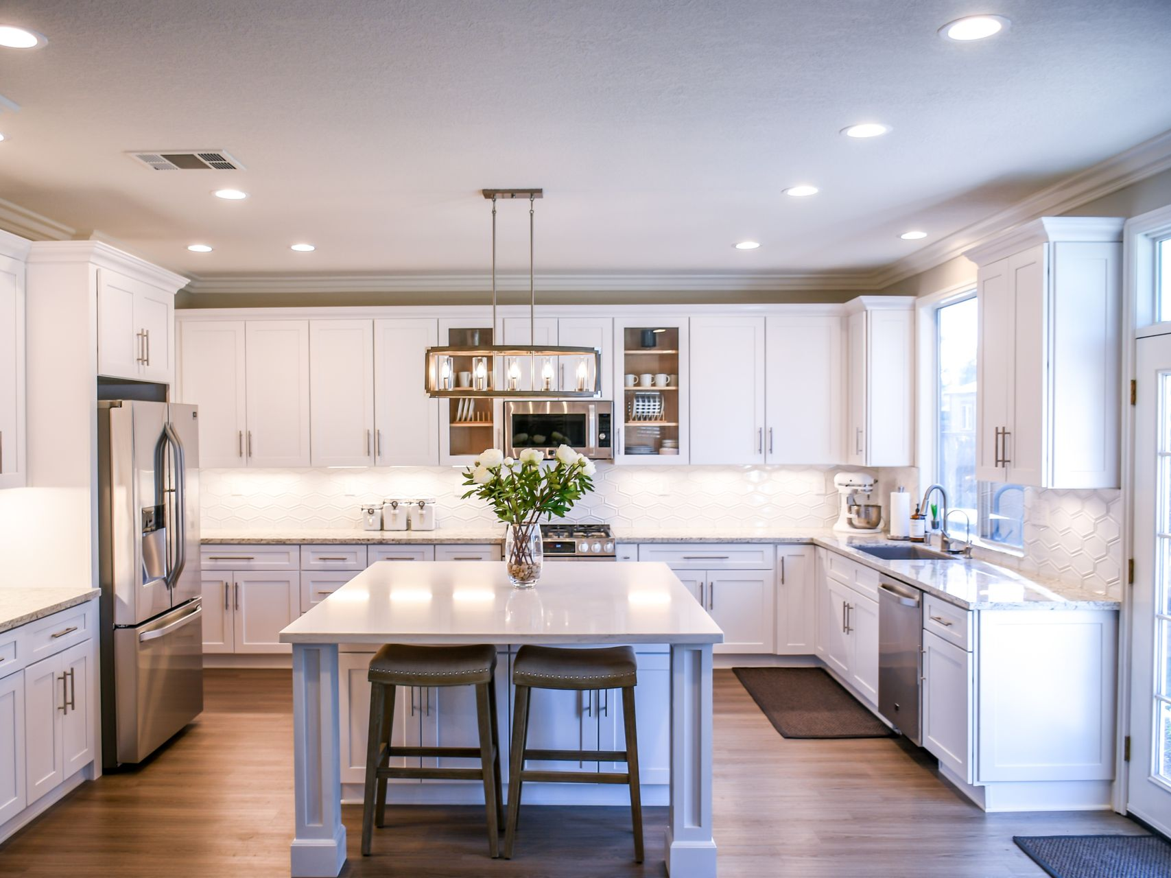 Bright white kitchen with island, cabinets, and stainless steel appliances.