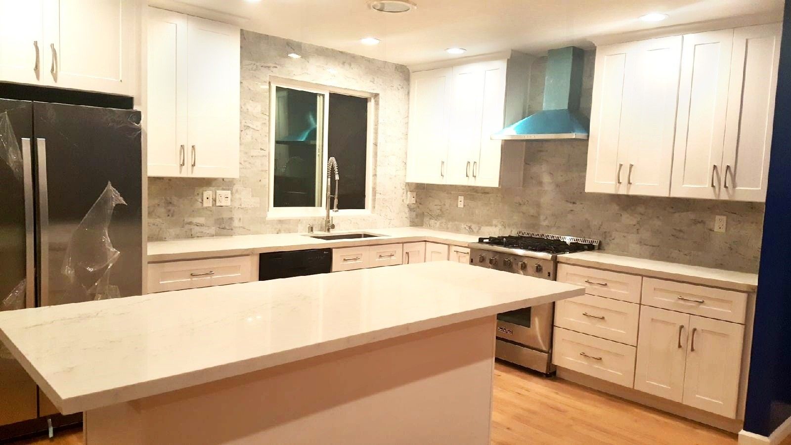 Modern kitchen with white cabinets, stainless steel appliances, and island.