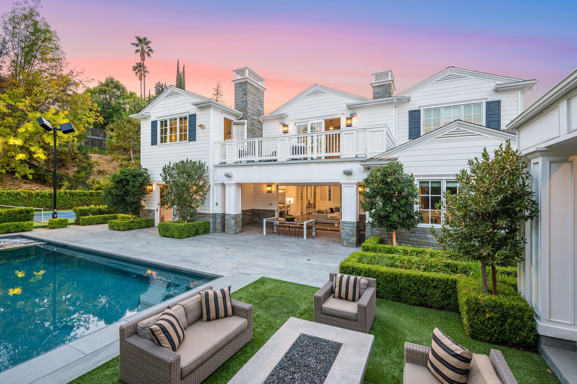 Luxury home exterior with pool and outdoor seating at dusk.