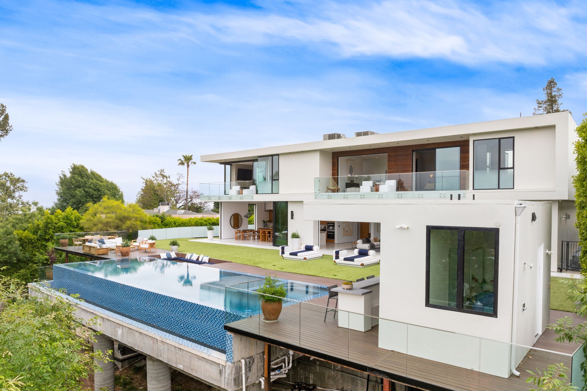 Modern white house with an infinity pool overlooking a cityscape.