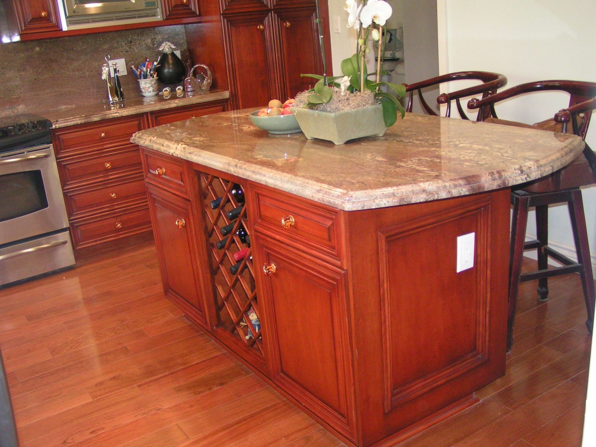 Kitchen island with granite countertop, built-in wine rack, and wooden cabinets.