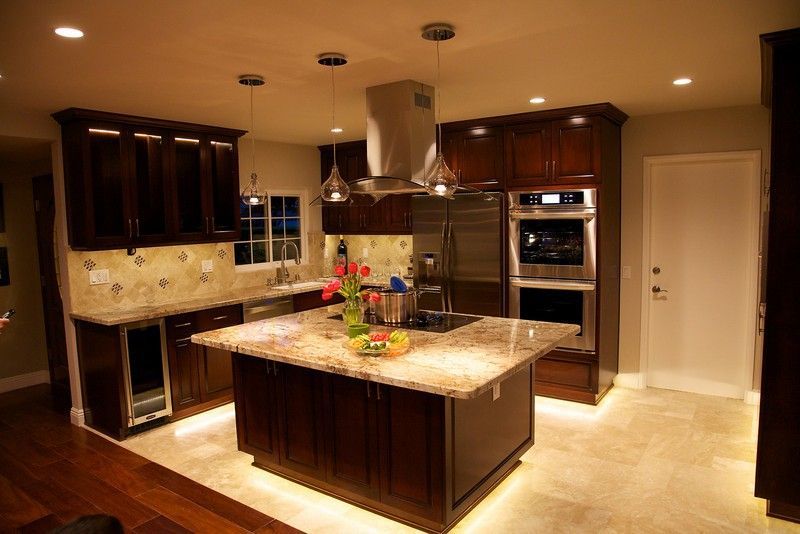 Dark wood kitchen with island, pendant lights, and stainless steel appliances.