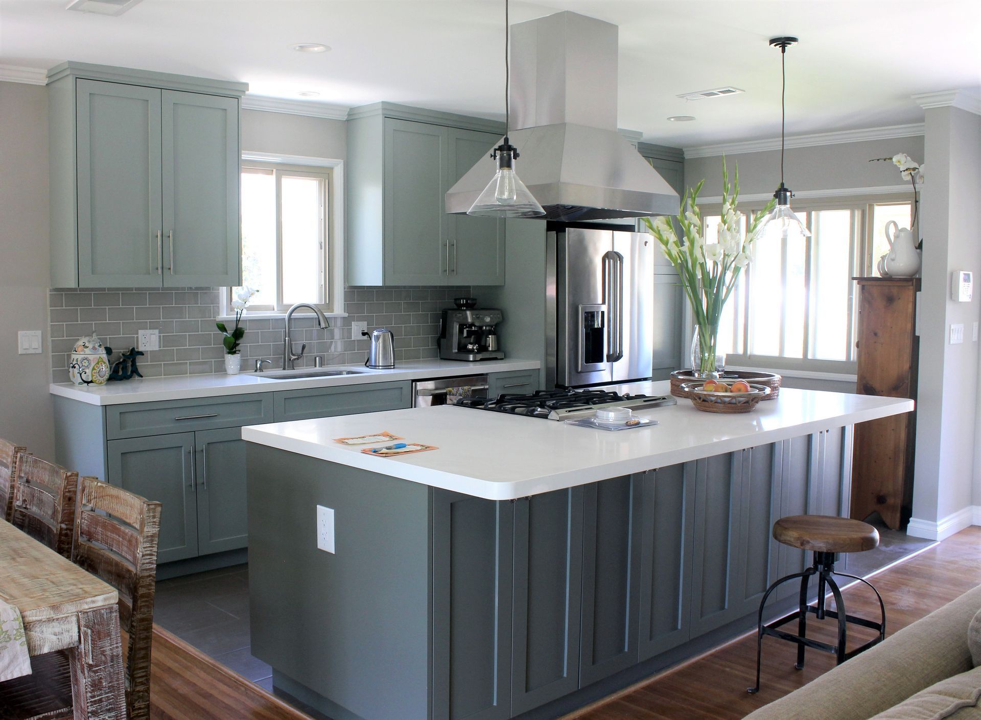 Modern kitchen with sage-green cabinets, white countertops, and a large island.