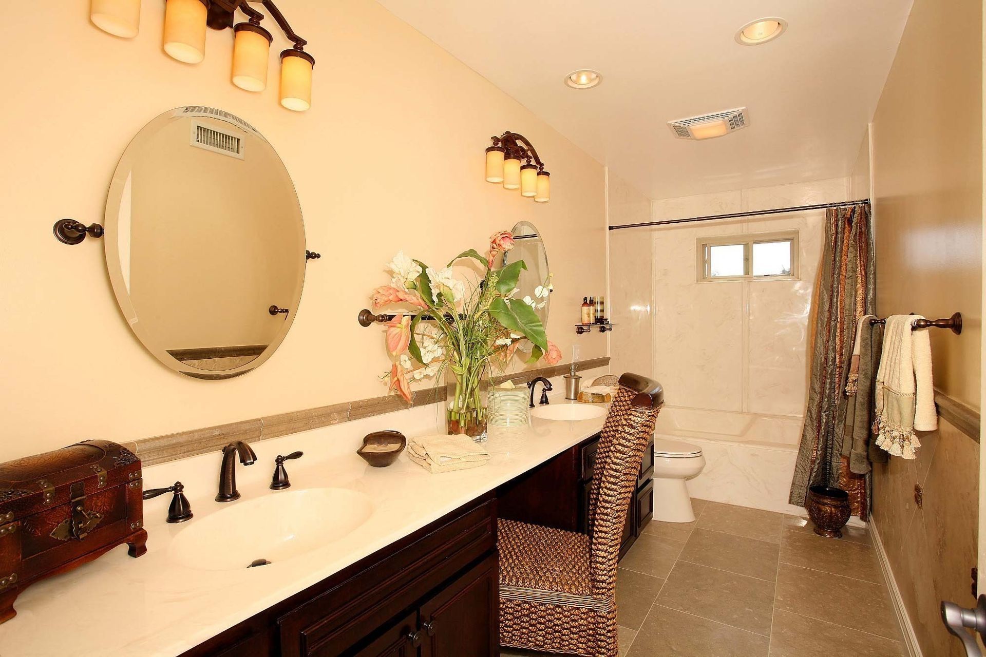 Bathroom with double sinks, large mirror, and tub. Brown cabinets, beige walls, and brown tile floor.