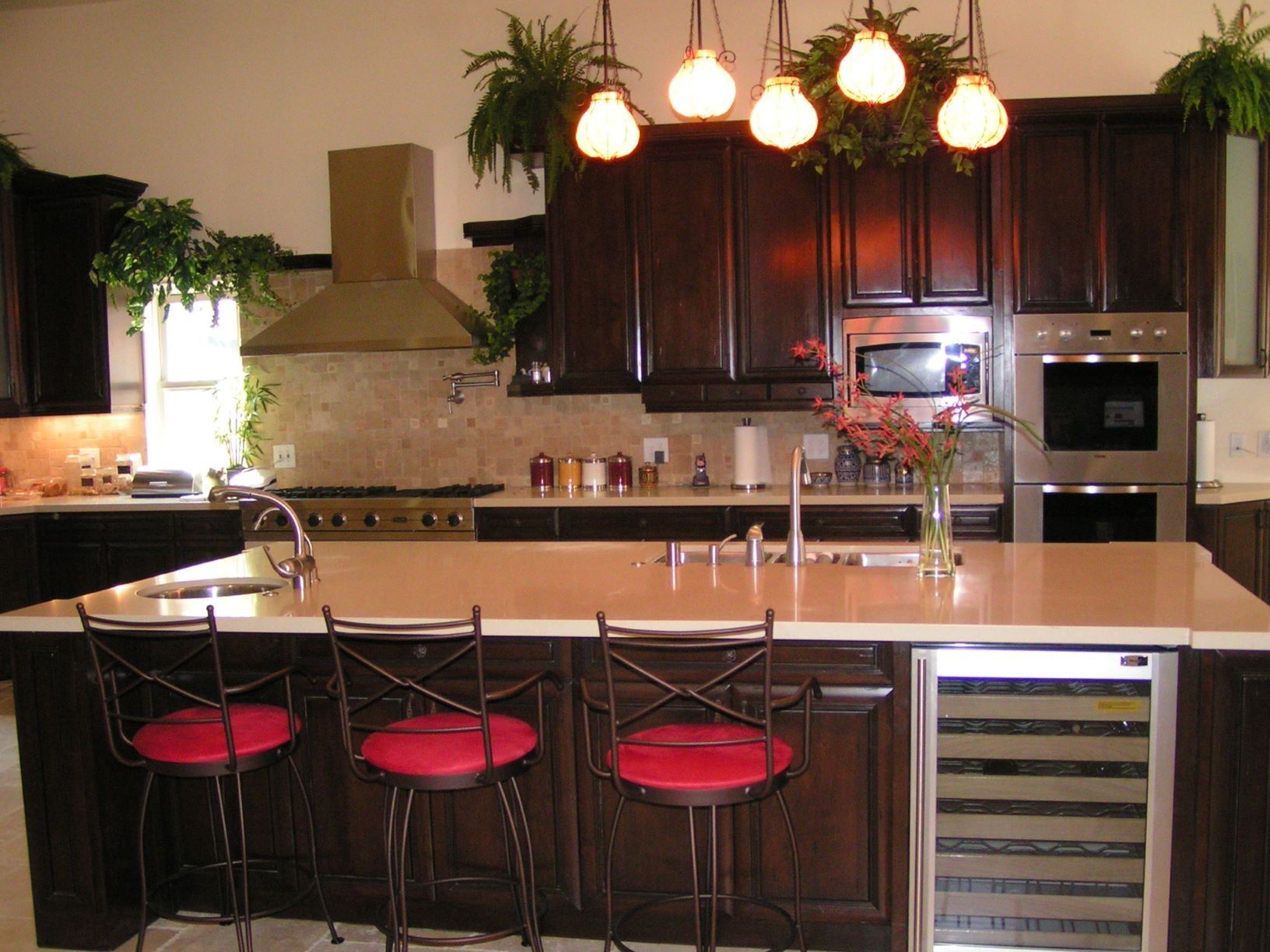 Kitchen with dark wood cabinets, island with red stools, and overhead lighting.