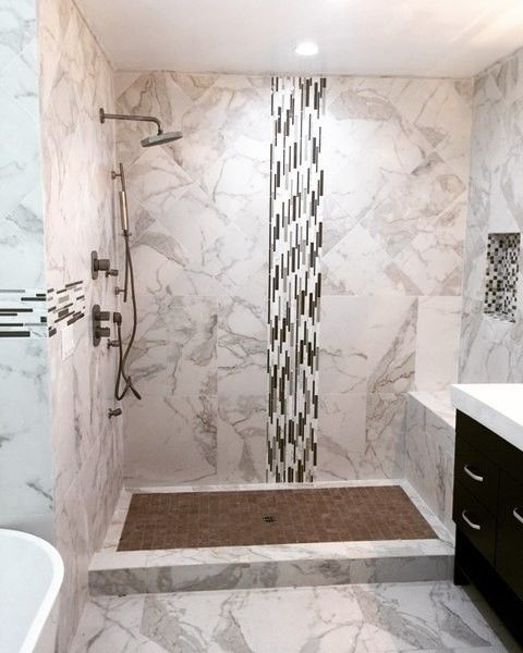 Marble-tiled shower with a bench, dark brown floor, and a mosaic stripe accent. Silver shower fixtures.