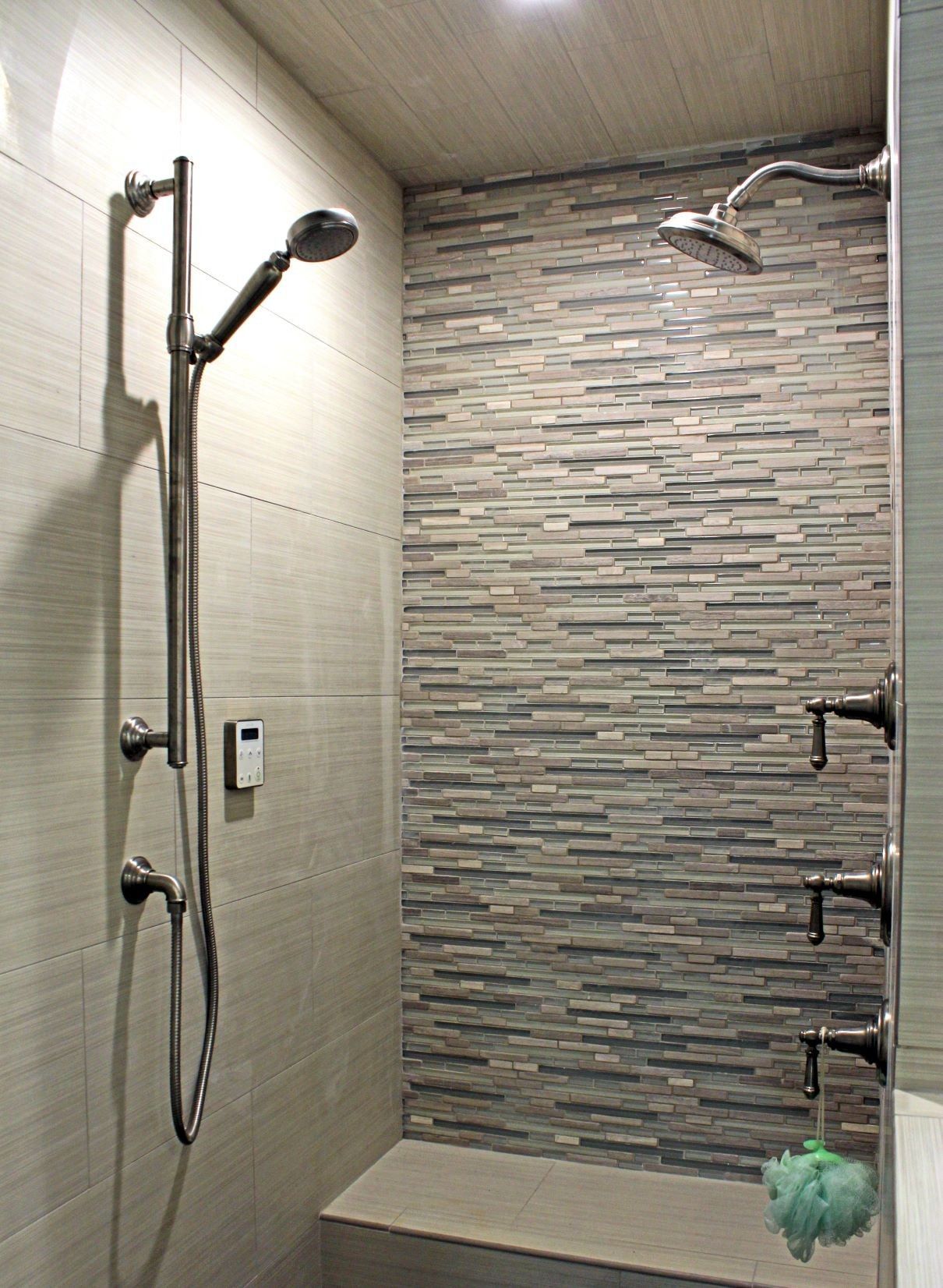 Modern shower with textured tile accent wall, bench, and multiple showerheads.