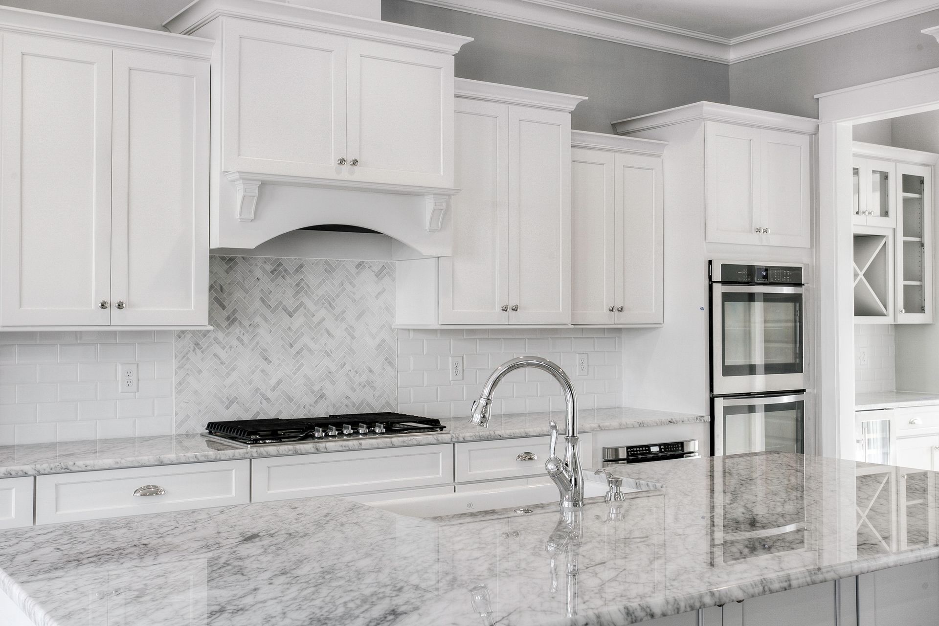 Modern remodeled kitchen with white cabinetry, marble countertops, and upgraded appliances.