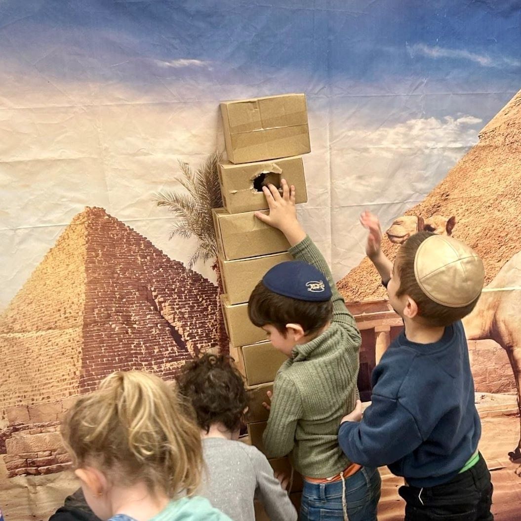 Children stacking cardboard blocks in front of a desert mural backdrop