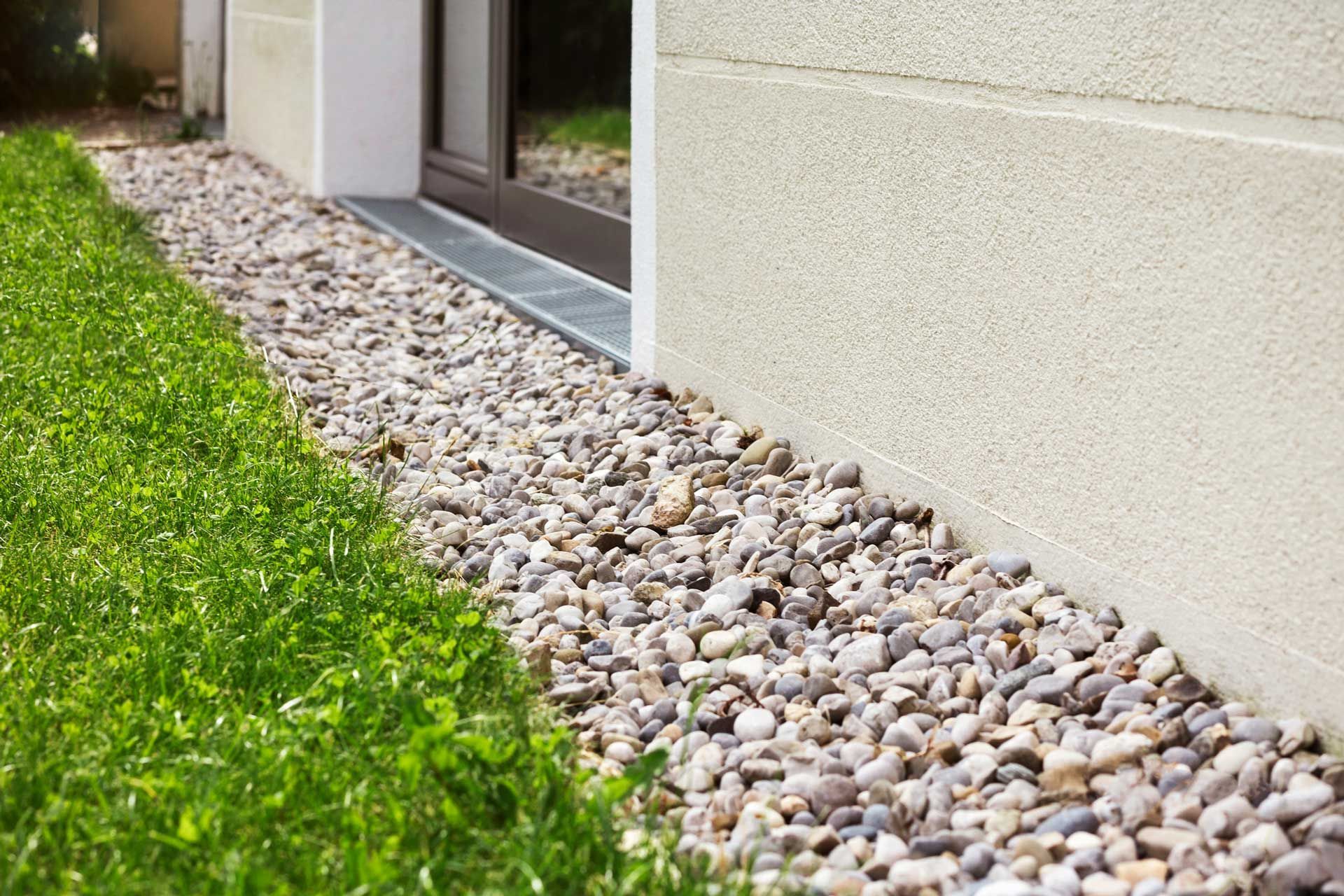 A sidewalk filled with rocks and grass next to a house.