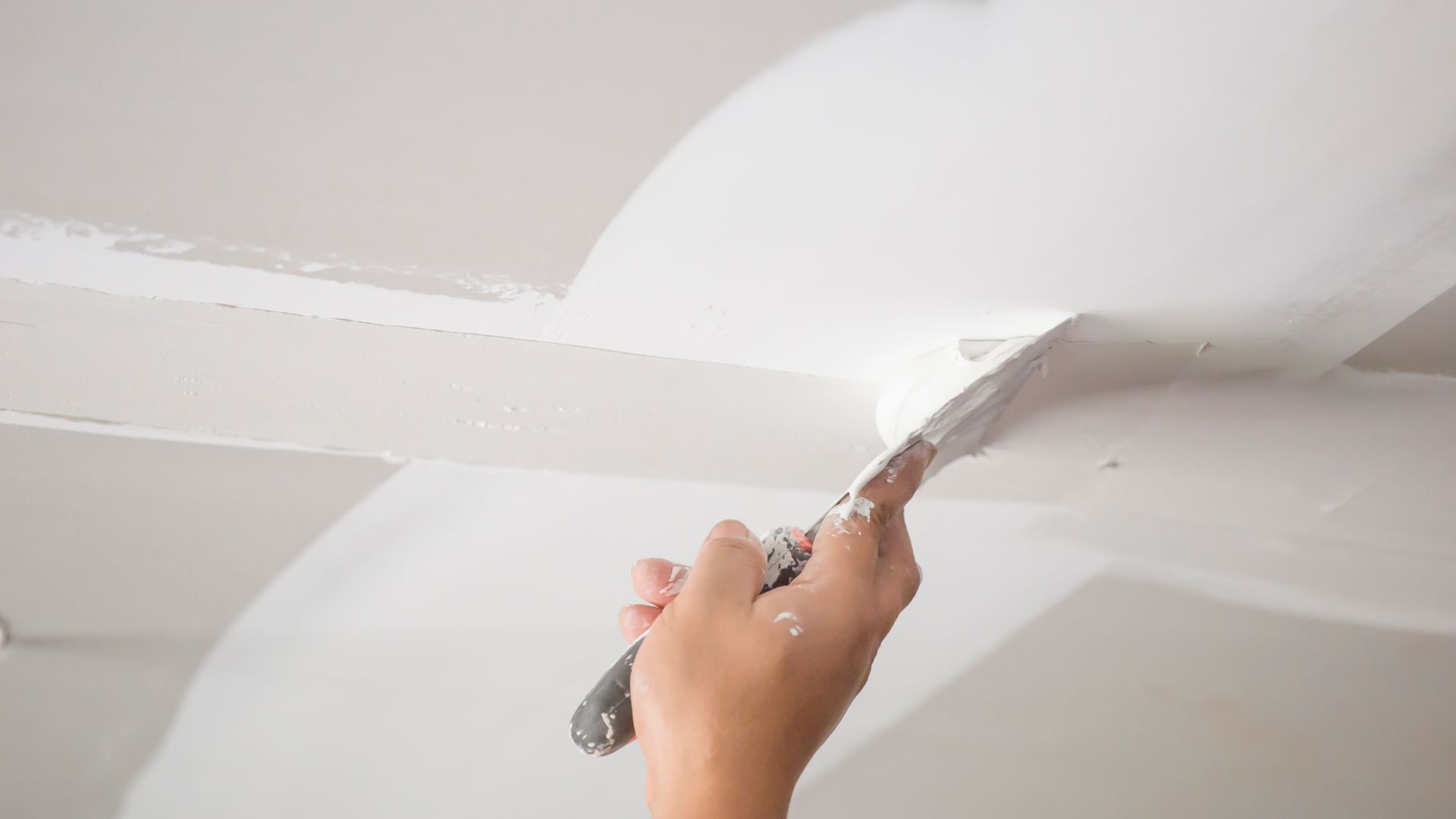 A person is painting a ceiling with a spatula.