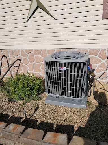 A large air conditioner is sitting outside of a house.