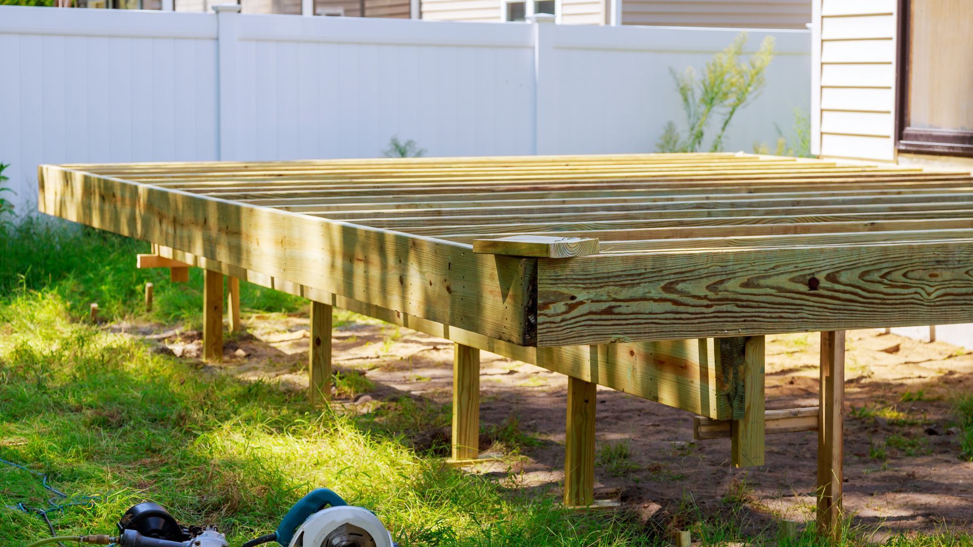 A wooden deck is being built in the backyard of a house.