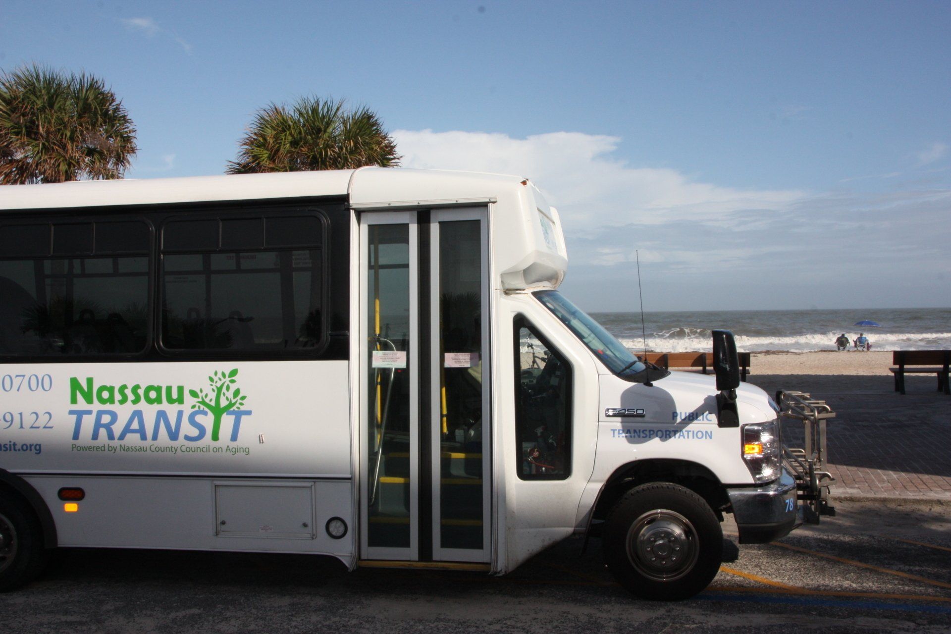White Nassau Transit bus parked by the beach.