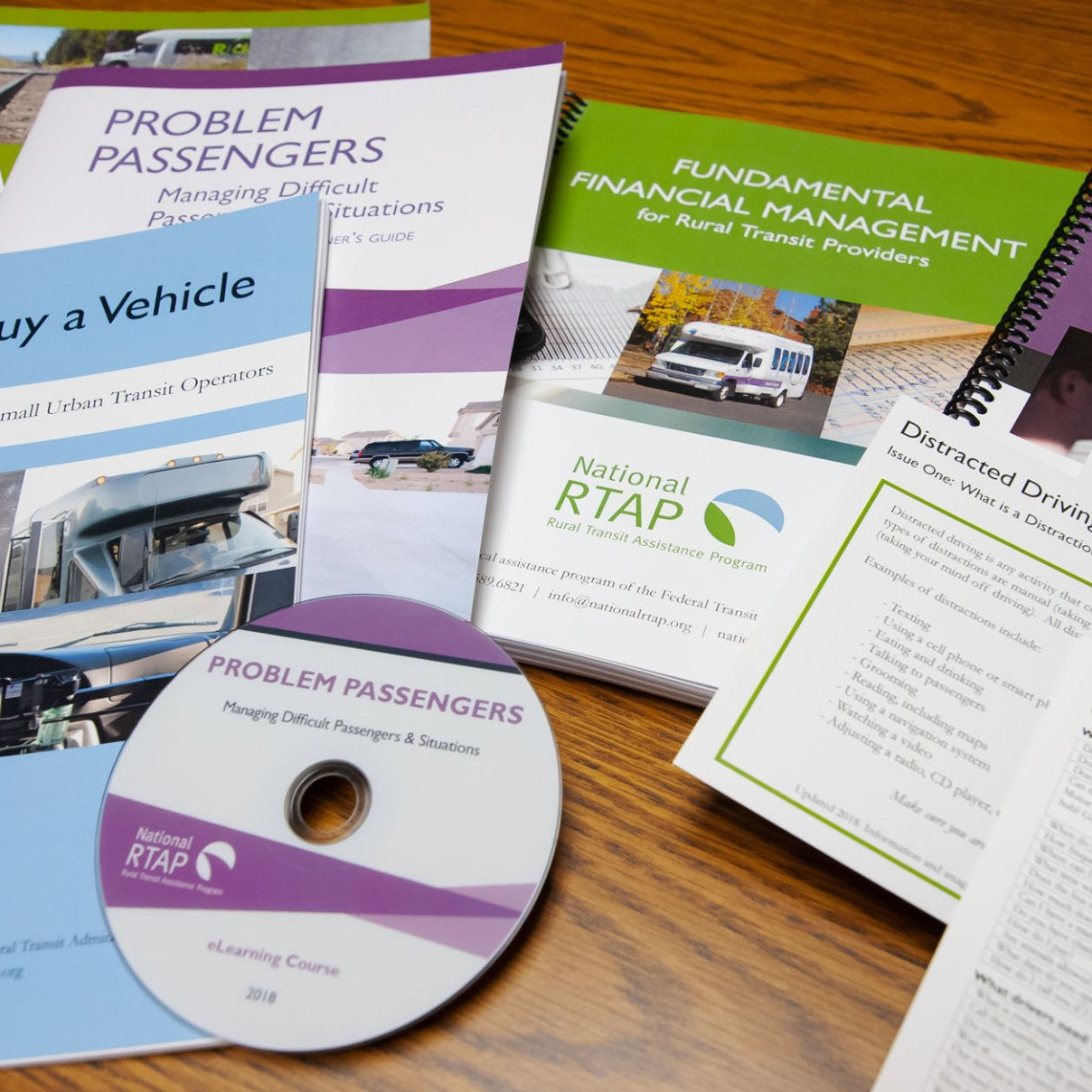 Documents and CD on wooden surface. Titles include 